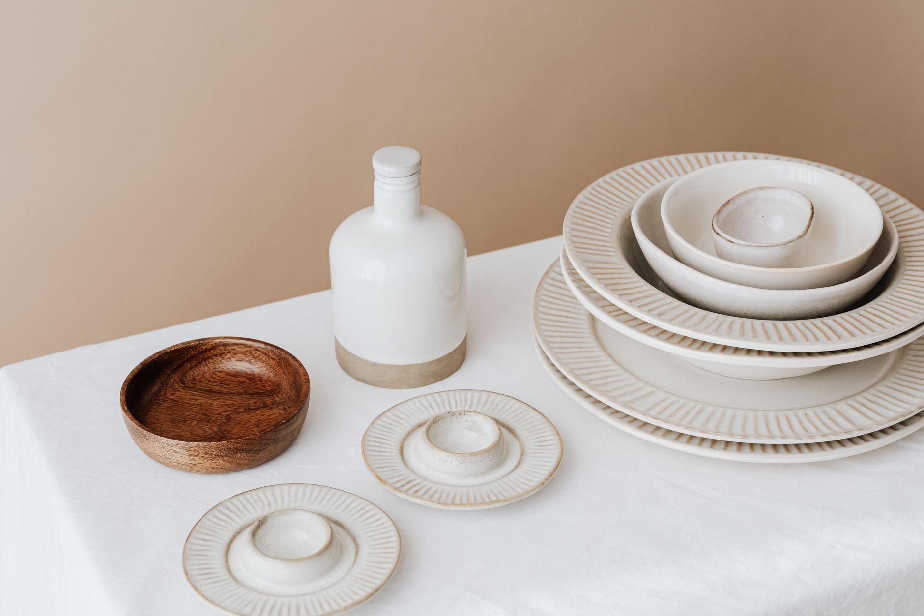 Minimalist arrangement of ceramic plates and bowls on a white tablecloth